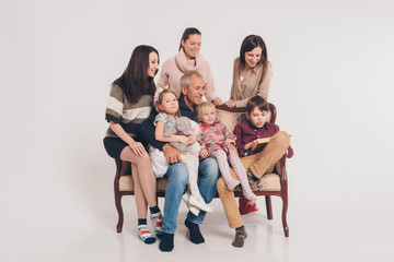 group of people on a white background: adults and children with toys sitting on the same couch