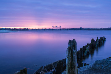 Sunrise Over river. Dawn on the coast. Early morning on the shore. Dramatic purple color  over river at dawn with clouds.
