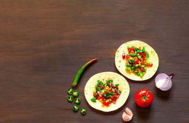 Traditional dish of Mexican cuisine. Corn tortilla tacos with vegetable filling on wooden background. 