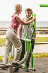 Man and woman exercising on elliptical trainer.