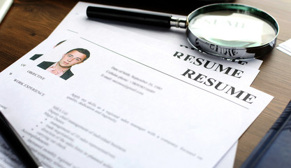 Resume (curriculum vitae, cv) and pen on a written wooden table.
