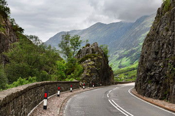 Curving Highway A82 through rock cliffs with Aonach Eagach Ridge mountains north of Glen Coe valley Scottish Highlands Scotland UK