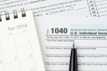 Obraz premium Pen on 1040 US individual income tax filling form with calendar, tax submission or revenue calculation concept