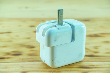 Old adapter charger damage on a wooden background.