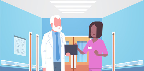 senior doctor and nurse medical team discussing in hospital corridor healthcare concept modern clinic interior portrait horizontal flat