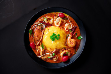 Thai Food Recipe .Thick rice soup, Tom Yum sauce, seafood .Thick egg rice On a black plate 