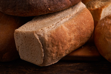 Different bread and wheat on the rustic table. Selective focus, close up