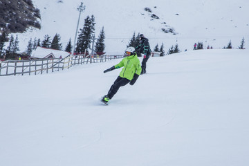 Two snowboarders running downhill on the snowy slope in the early morning