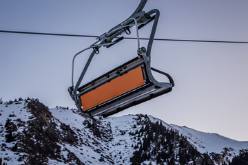 Empty ski lift with an empty orange commercial banner in front of morning sky