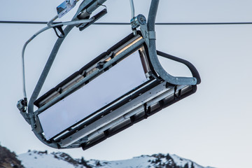 Empty ski lift with an empty white commercial banner in front of morning sky