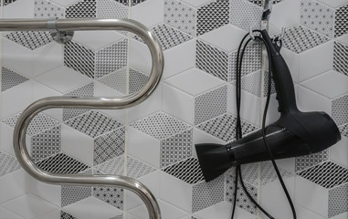 big black hair dryer and hand rail for towel in hotel bathroom