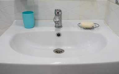 white ceramic sink in bathroom with plastic glass for brush and soap for hand cleaning