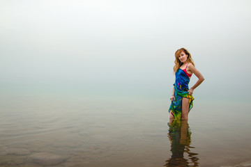 Nice woman stands in water of Dead Sea in Jordan and fog