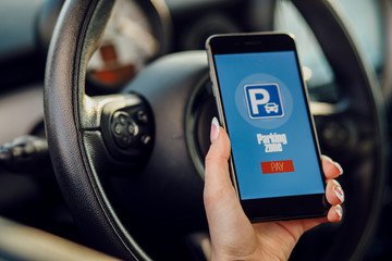 Girl using smartphone app to pay for the parking.