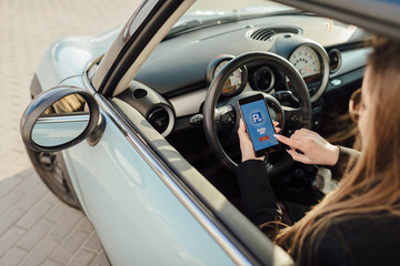 Girl using smartphone app to pay for the parking.