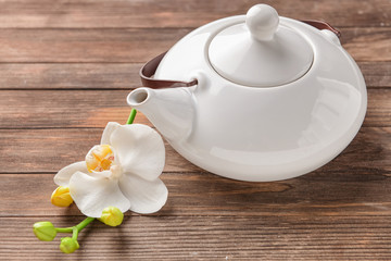 Obraz na płótnie Canvas Teapot and beautiful orchid flower on wooden background