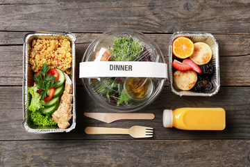 Containers with delicious food on wooden background