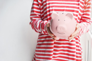 Woman with piggy bank near window. Concept of savings