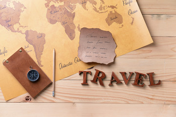 Notebook, old paper sheet, compass and world map on wooden background. Travel concept
