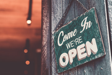 Open sign broad hanging on wood door front of cafe.