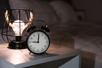 Naklejka premium Alarm clock on bedside table in evening