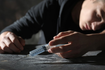 Male suicider with syringe at table
