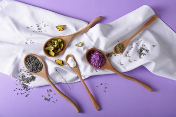 Spoons with natural ingredients for cosmetic on color background