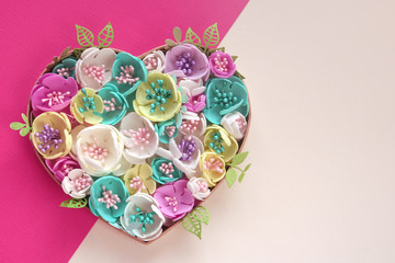 heart of artificial flowers handmade on color beige pink paper background. Copy space...