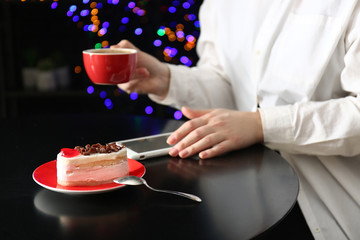 Young woman with mobile phone drinking coffee at table