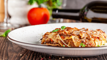 The concept of Italian cuisine. Lasagna with minced meat, bechamel sauce and parmesan cheese. Close up. Serving dishes in a restaurant in a white plate. copy space