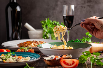 concept of Italian cuisine. Tagliatelle with vegetables, tomatoes, olives and parmesan cheese. Decorated with parsley. Serving dishes in a restaurant in a green plate.  copy space