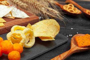 Mix of snacks : pretzels , crackers , chips  and nachos on the table