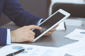 Businessman using tablet at meeting, closeup of hands. Business operations concept