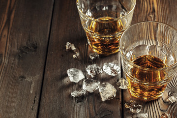 Whiskey and ice on rustic wood background