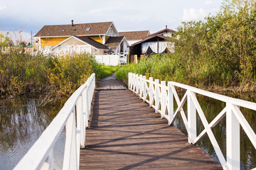 Fototapeta na wymiar Village, nature and country life concept - long wooden bridge and houses