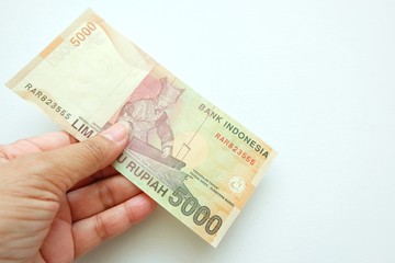  Woman hand holding  Indonesia banknote on white background. 