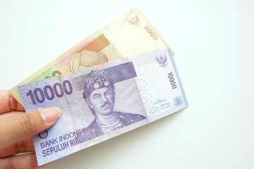  Woman hand holding  Indonesia banknote on white background. 