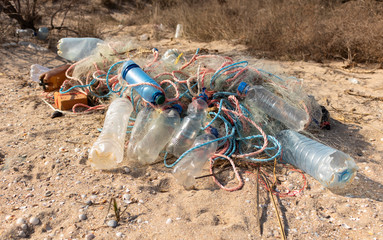 Empty plastic bottles and fishing nets on the sand. Garbage on the beach. Dirty sea shore. Environmental pollution. Save the Planet. Ecological problem. Nature theme.