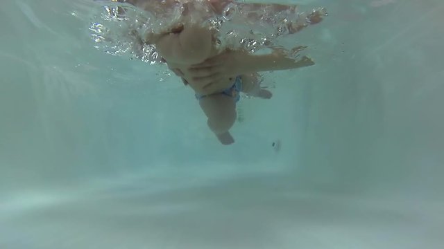 Baby boy diving under the water with mother at bath. An underwater Slowmotion shot