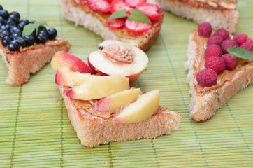 different delicious toasts on green or pink crimson background. Healthy sandwich for breakfast or snack. Toast with raspberries, strawberries, banana and blueberries and peanut butter. picnic concept