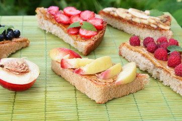 different delicious toasts on green or pink crimson background. Healthy sandwich for breakfast or snack. Toast with raspberries, strawberries, banana and blueberries and peanut butter. picnic concept