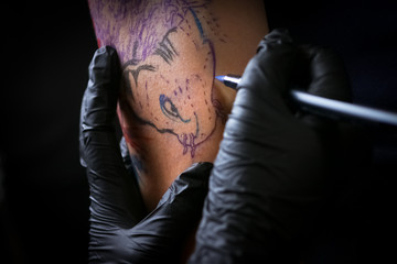 Female tattoo artist making tattoo on a men’s arm