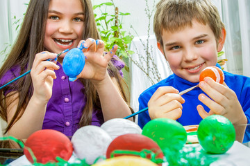 Mother and her children paint easter eggs