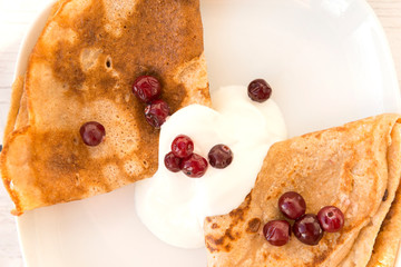 pancakes in sour cream and cranberries on a plate