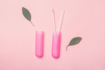transparent reusable glass straw and cleaning brush in pink container isolated  on pink background, eco friendly lifestyle, zero waste concept, top view, flat layout