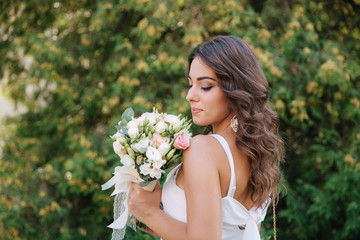 Gorgeous female in white dress slime. Beautiful girl hold a bouquet of flowers in hands