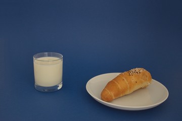 Glass of milk and bread on the blue background