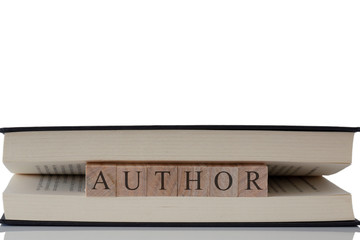 Author written on wooden blocks inside a book isolated on a white background with reflection