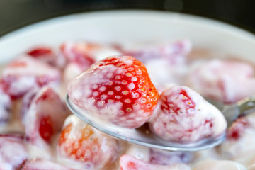 Red strawberry and white yogurt brulee. Fruit dessert on breakfast with wedges of perfectly ripe in season strawberry, closeup
