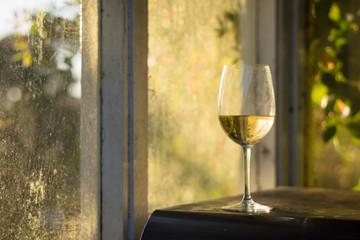 Glass of white wine on a table with golden back lighting